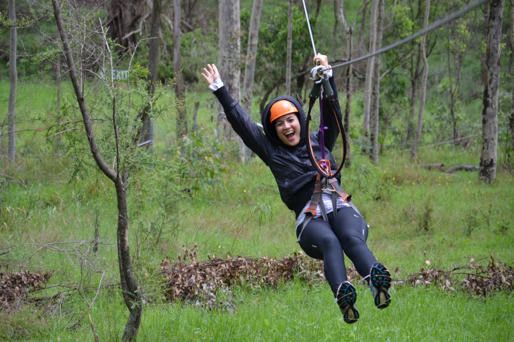Tree Tops ropes courses. Lady yahooing on the flying fox zip line on a Sydney team Building Activities day.